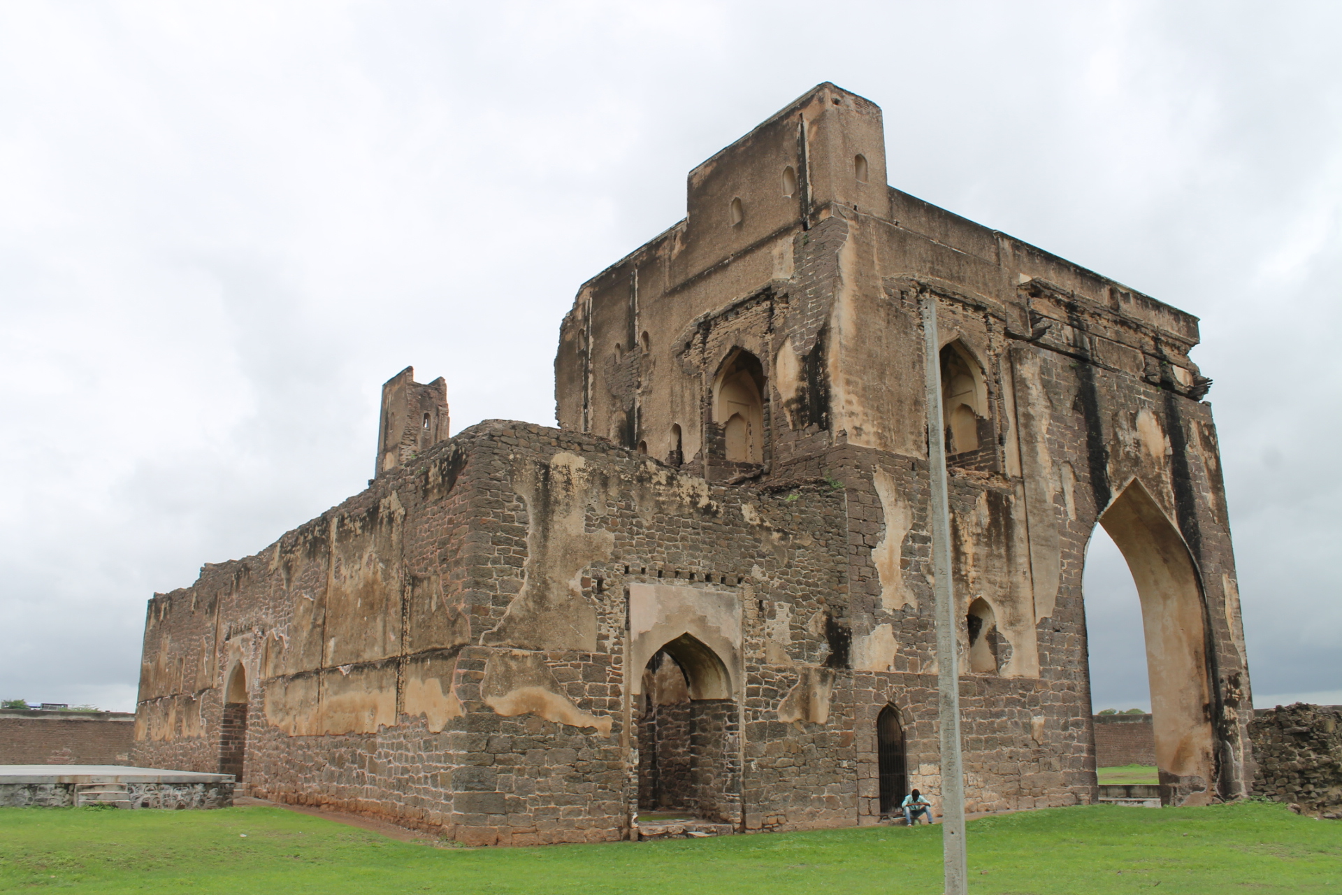 Ruins of a historic stone church stand on a green field, showcasing Indian culture and history.